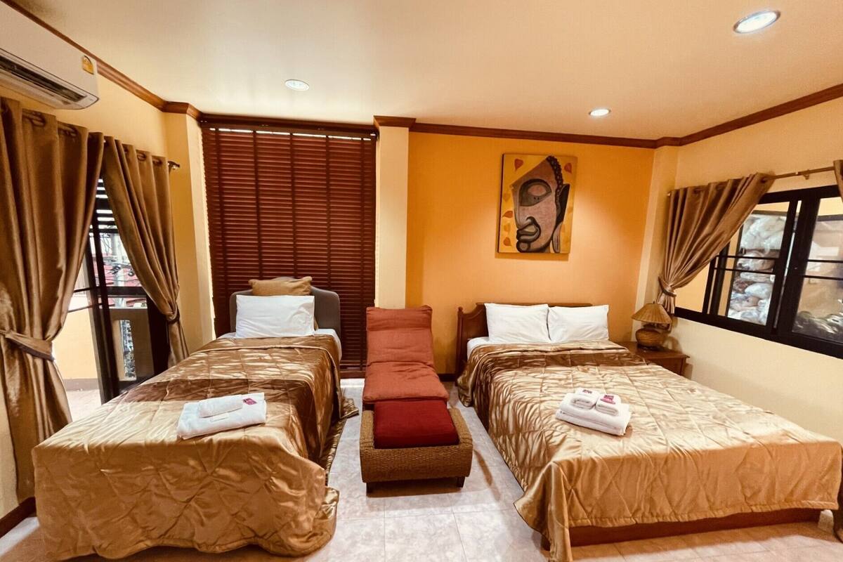 Ein Hotelzimmer mit zwei Einzelbetten, einer Schlafcouch, einem Fenster mit Vorhängen und einem Gemälde an der Wand.
