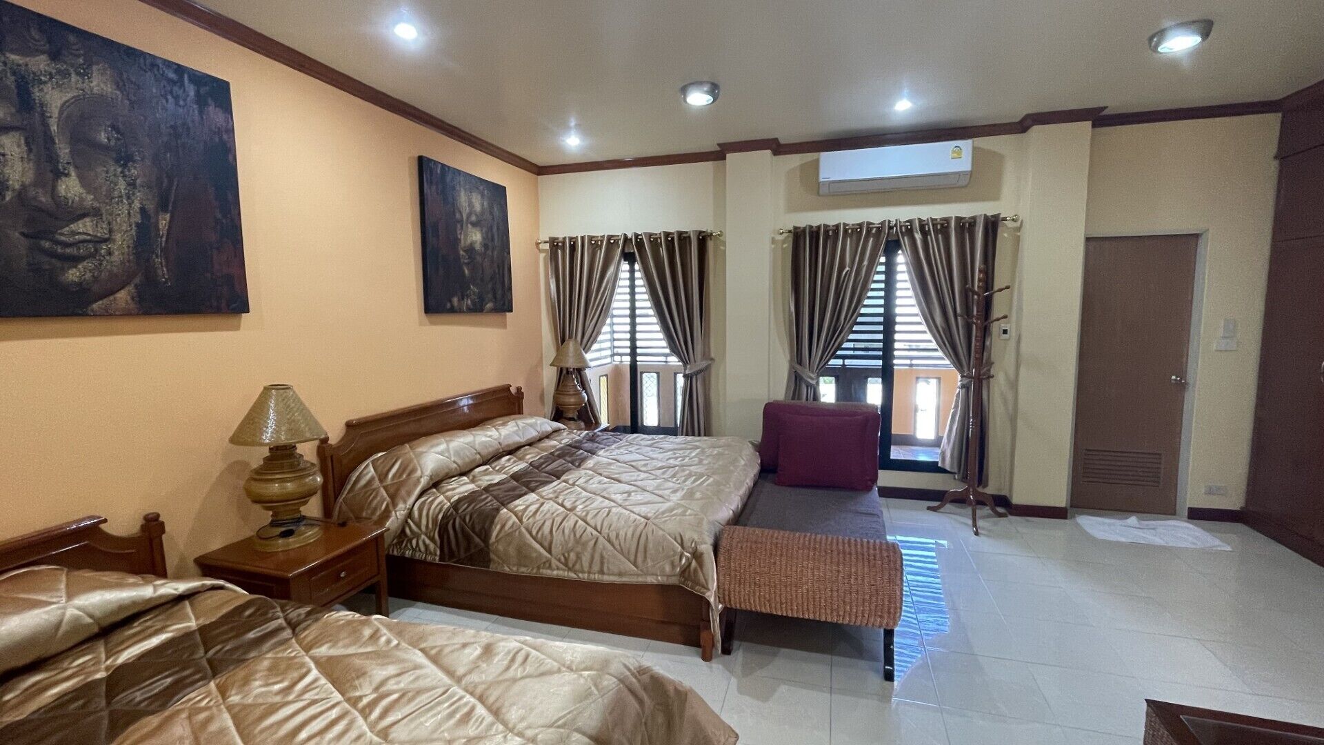 A hotel room with two beds, a bench, a lamp, and artwork on the walls.