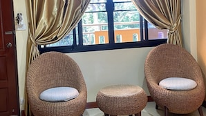 A room with three wicker chairs and a small ottoman, a window with curtains, and a door. - Mini Cost Apartment & Guesthouse (Chiang Mai)