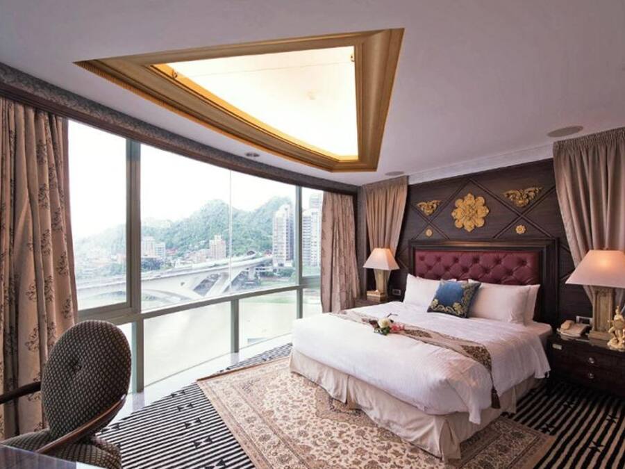 Habitación de hotel con una cama grande, vistas a la ciudad y un diseño de techo moderno.