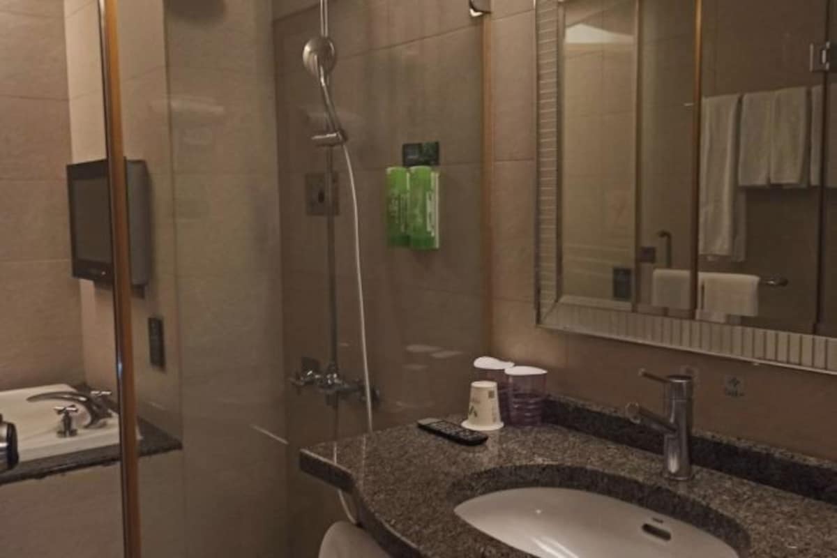 Un baño moderno con encimera de granito, lavabo, espejo y ducha.