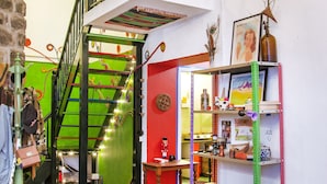 Ein mehrgeschossiges Interieur mit einer Treppe, Regalen voller Gegenstände und bunten Teppichen.