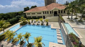 A large building with a swimming pool, surrounded by palm trees and a clear sky. - Splendido Tower 2 Ann's Unit  (Laurel)