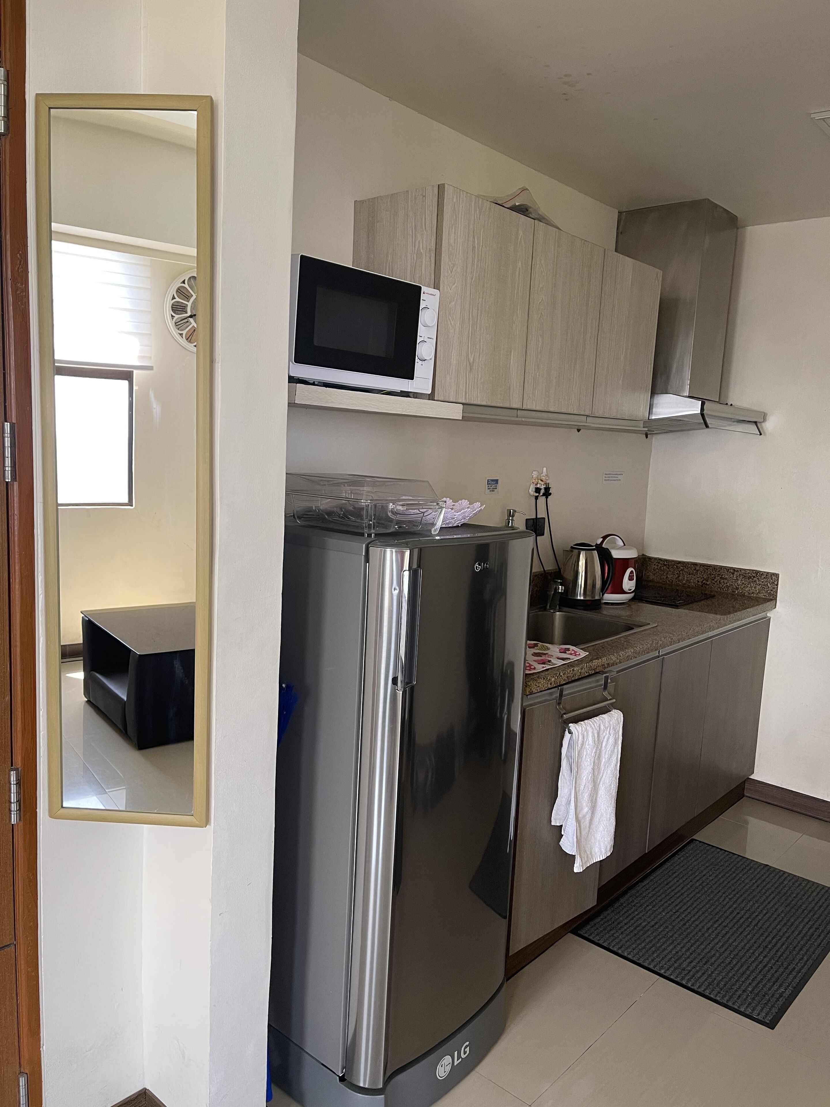 A modern kitchen with a stainless steel refrigerator, a microwave, and wooden cabinets.