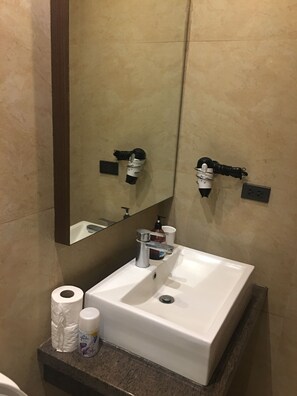 A bathroom with a white sink, a mirror, a towel dispenser, and a toilet paper holder. - Splendido Tower 2 Ann's Unit  (Laurel)