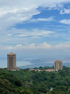 A view of two high-rise buildings surrounded by lush greenery and a body of water in the distance. - Splendido Tower 2 Ann's Unit  (Laurel)