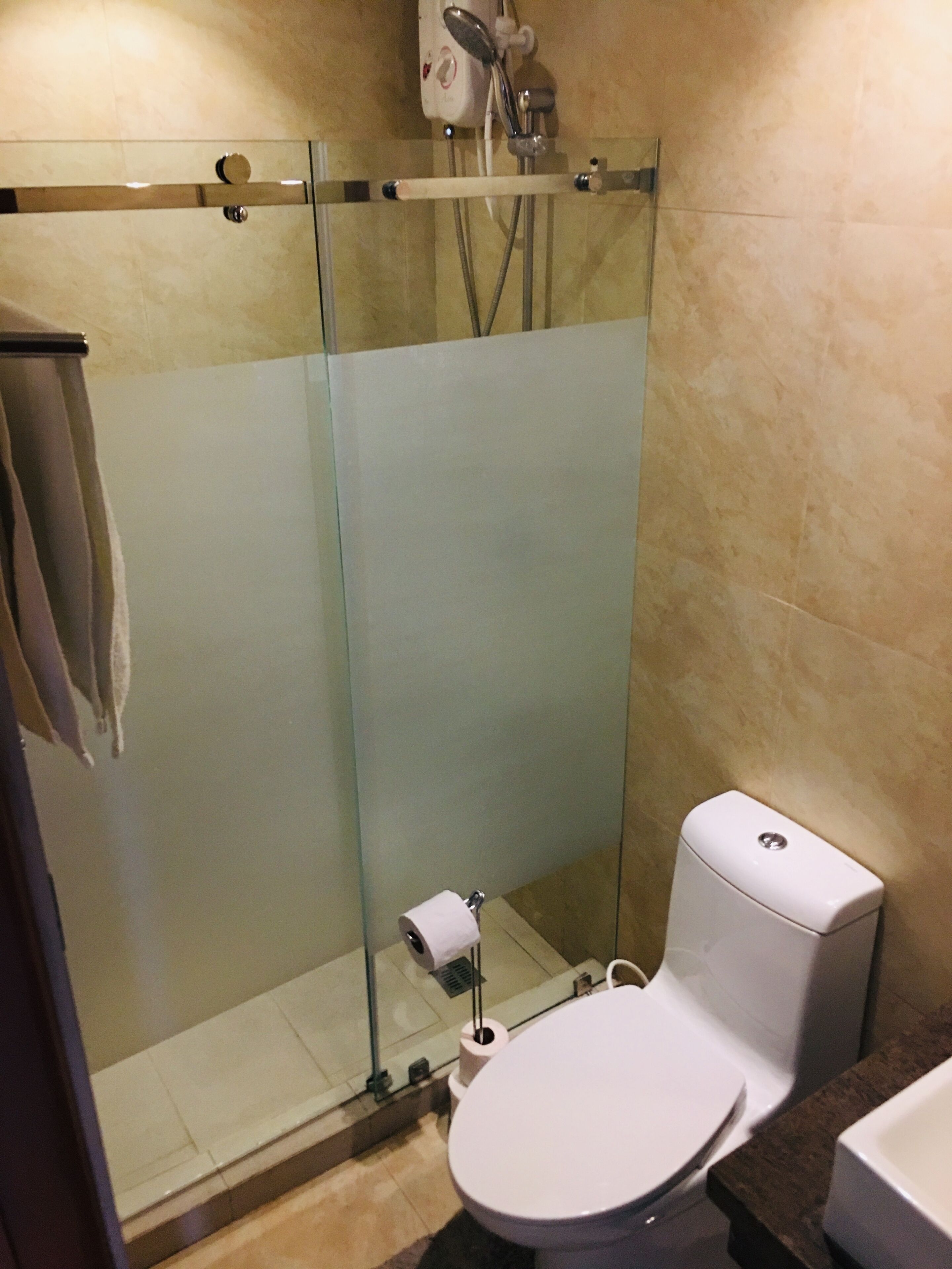 A bathroom with a glass-enclosed shower, a toilet, and a sink.