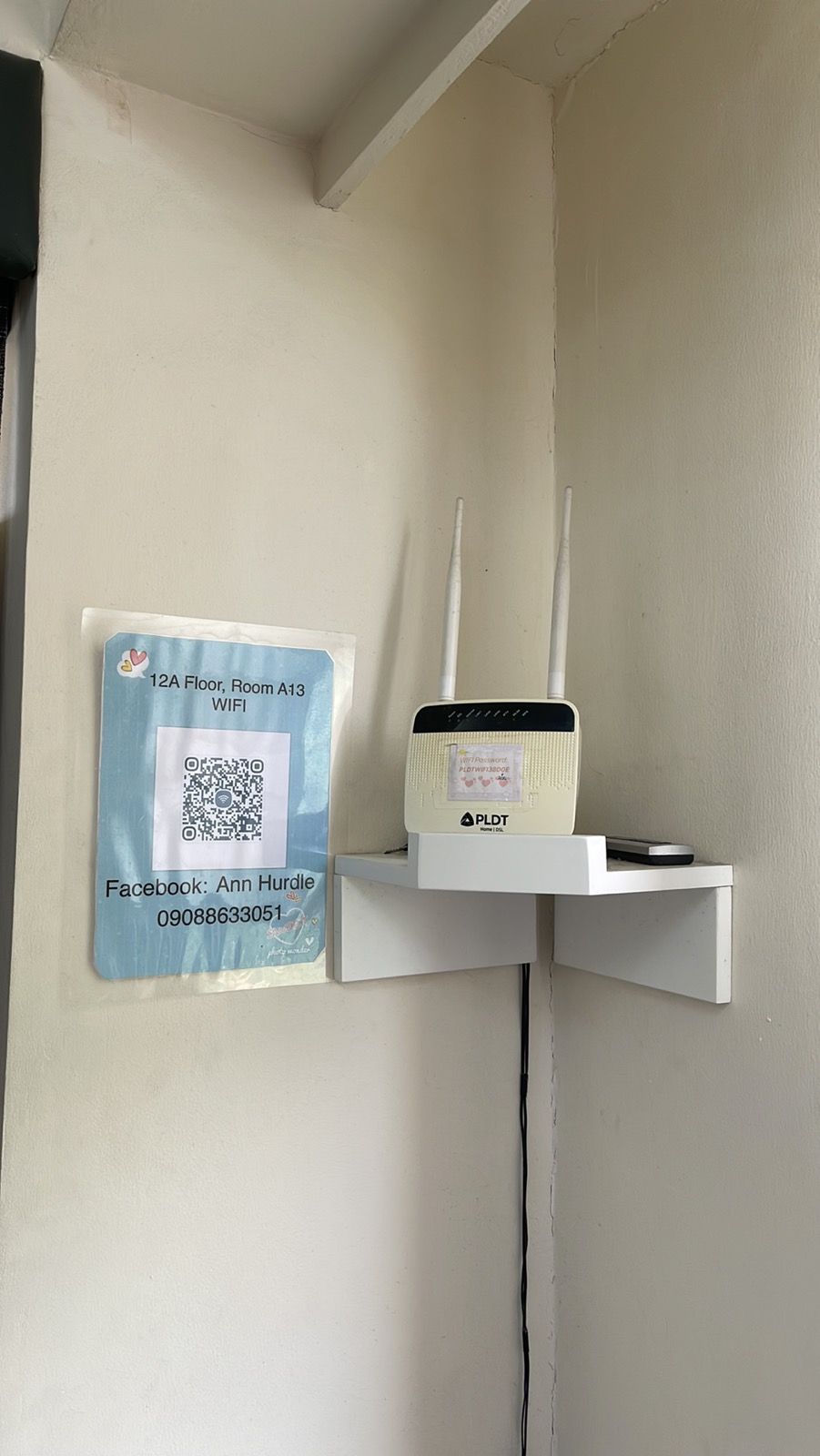 A white wall with a QR code and a Facebook contact card for Ann Hurdle in a corner.