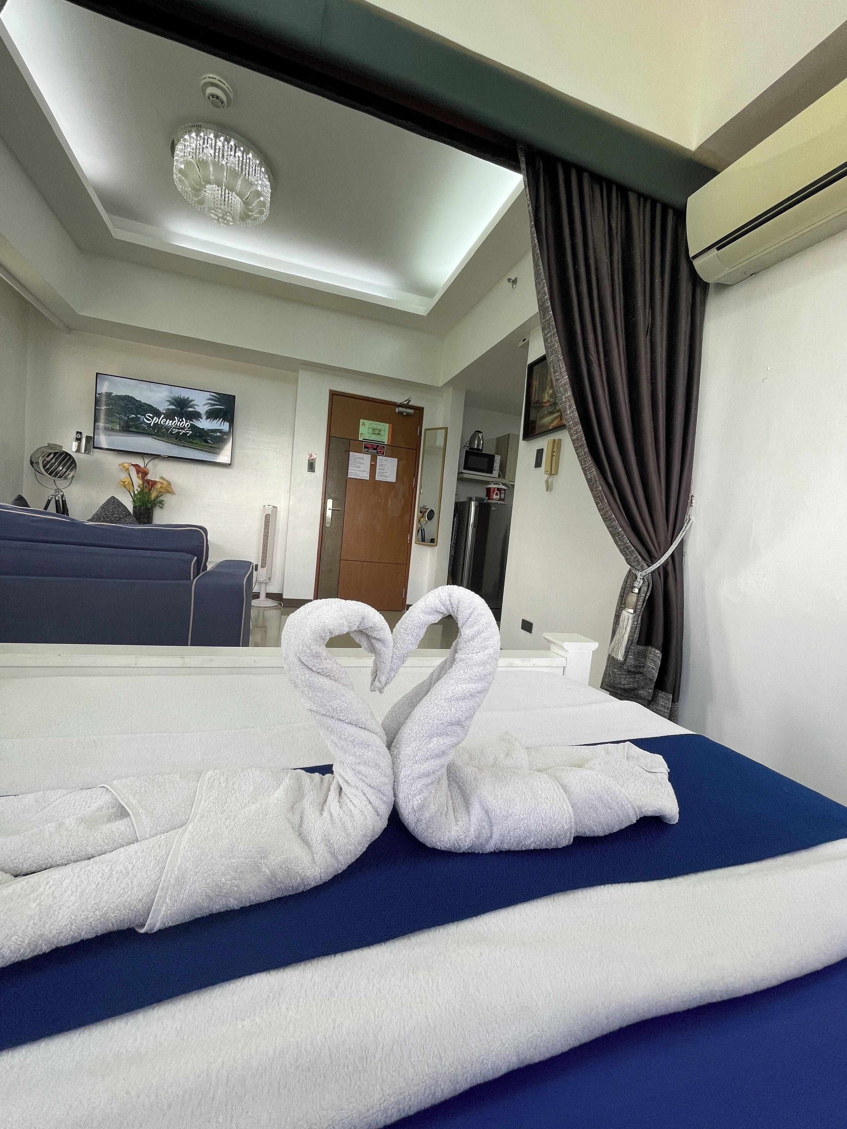 A hotel room with a bed, a TV, a desk, and a mirror.
