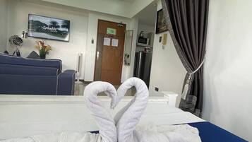 A hotel room with a bed, a TV, a desk, and a mirror.
