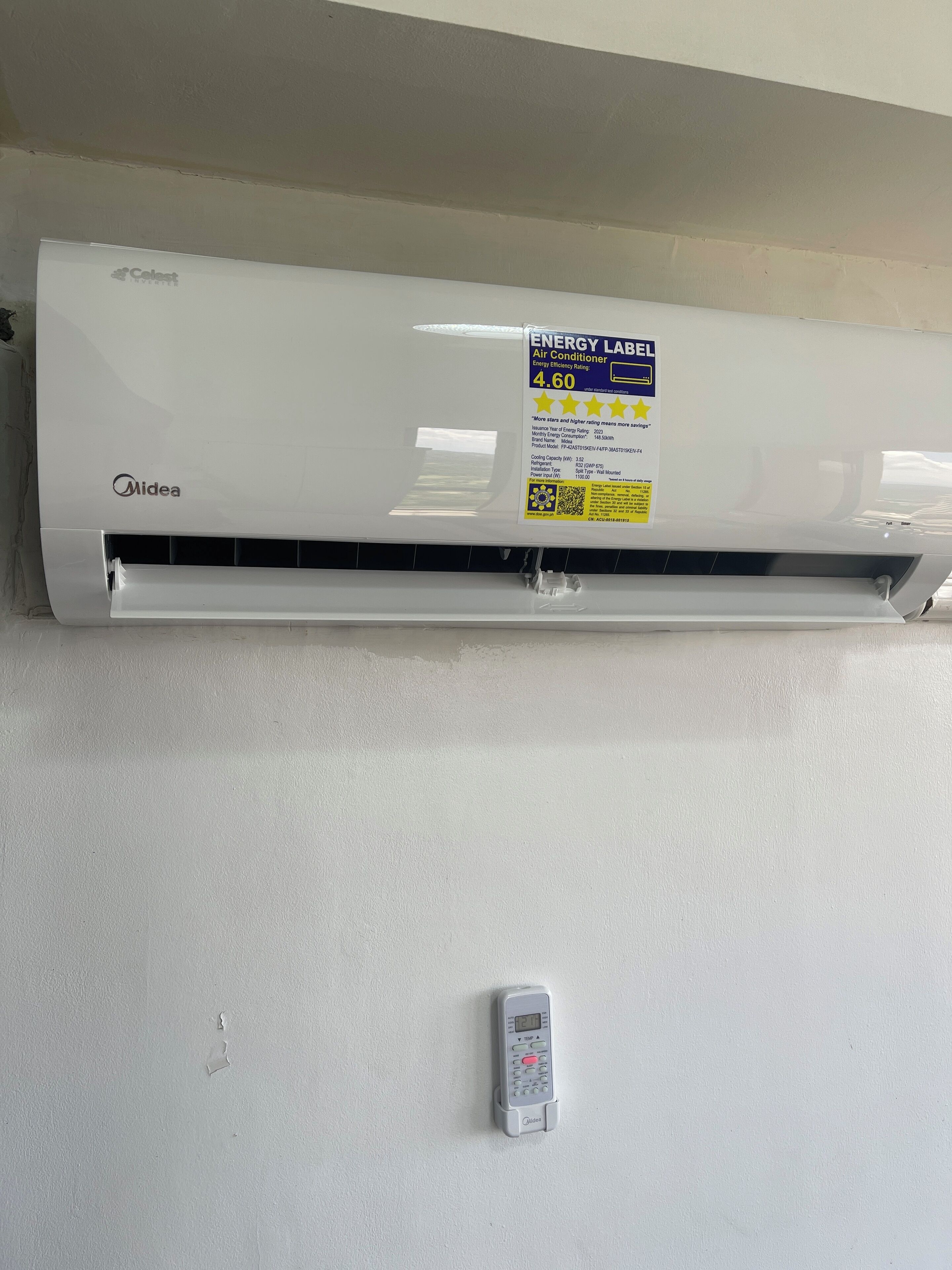 A wall-mounted air conditioner with an energy efficiency label and a remote control on the wall.
