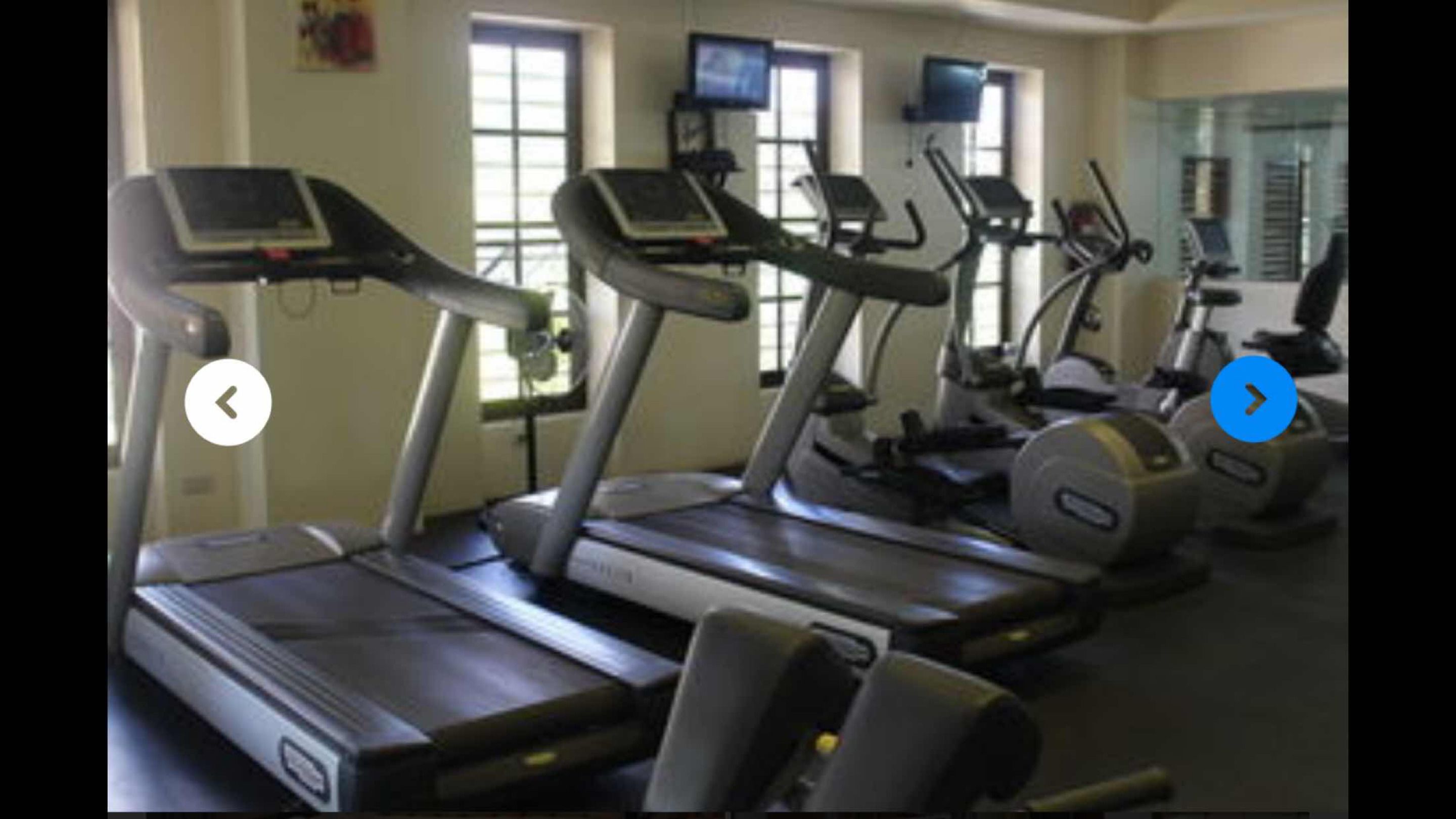 Une salle de sport équipée de plusieurs tapis de course et d’appareils d’exercice.