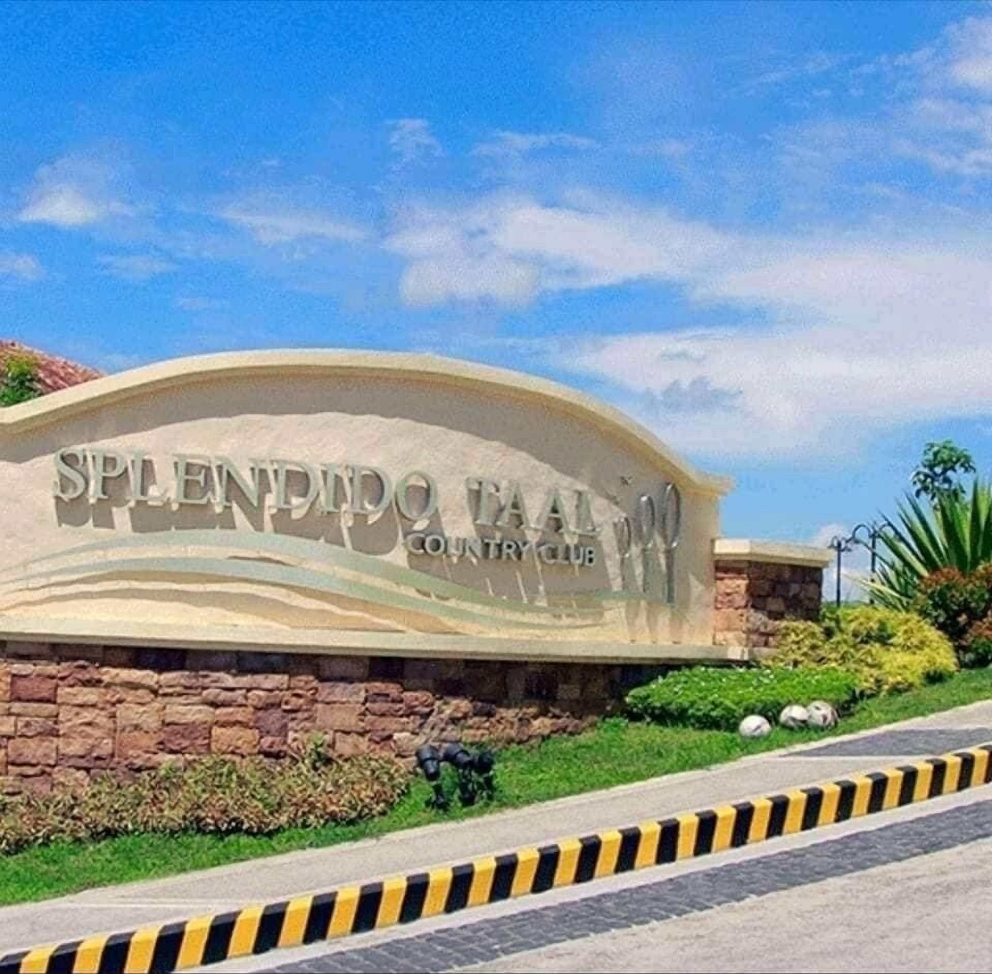 A sign for Splendid Country Club with a curved design and a stone wall base.