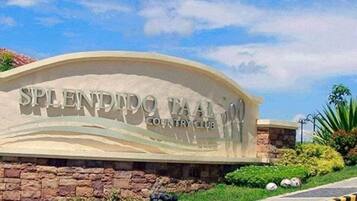 A sign for Splendid Country Club with a curved design and a stone wall base.