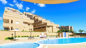 Zona de piscina con un edificio al fondo.