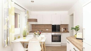 A compact kitchen with white cabinets, a wooden countertop, a built-in oven, and a dining area with a table and chairs.