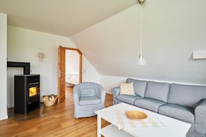 Un salon chaleureux avec une cheminée, un canapé gris, une table basse blanche et un plancher en bois.