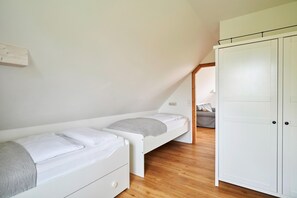 A bedroom with a loft bed, a wardrobe, and a wooden floor.
