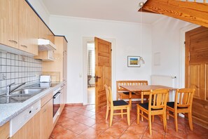 A kitchen with wooden cabinets, a granite countertop, and a dining area with a wooden table and chairs.