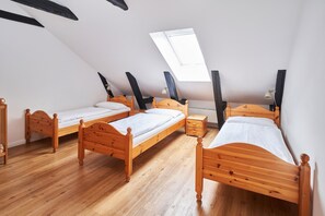 Quarto com três camas de madeira, um claraboia e um radiador.