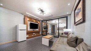 Una sala de estar moderna con un sofá, una mesa de centro, un televisor y una cocina integrada.