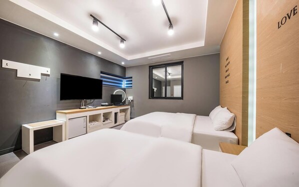 A modern hotel room with two beds, a TV, a desk, and a large window. - Rings Hotel (Gunsan)