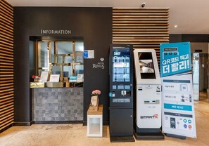 A hotel reception area with a self-check-in kiosk, a digital information board, and a sign promoting QR code check-in. - Rings Hotel (Gunsan)