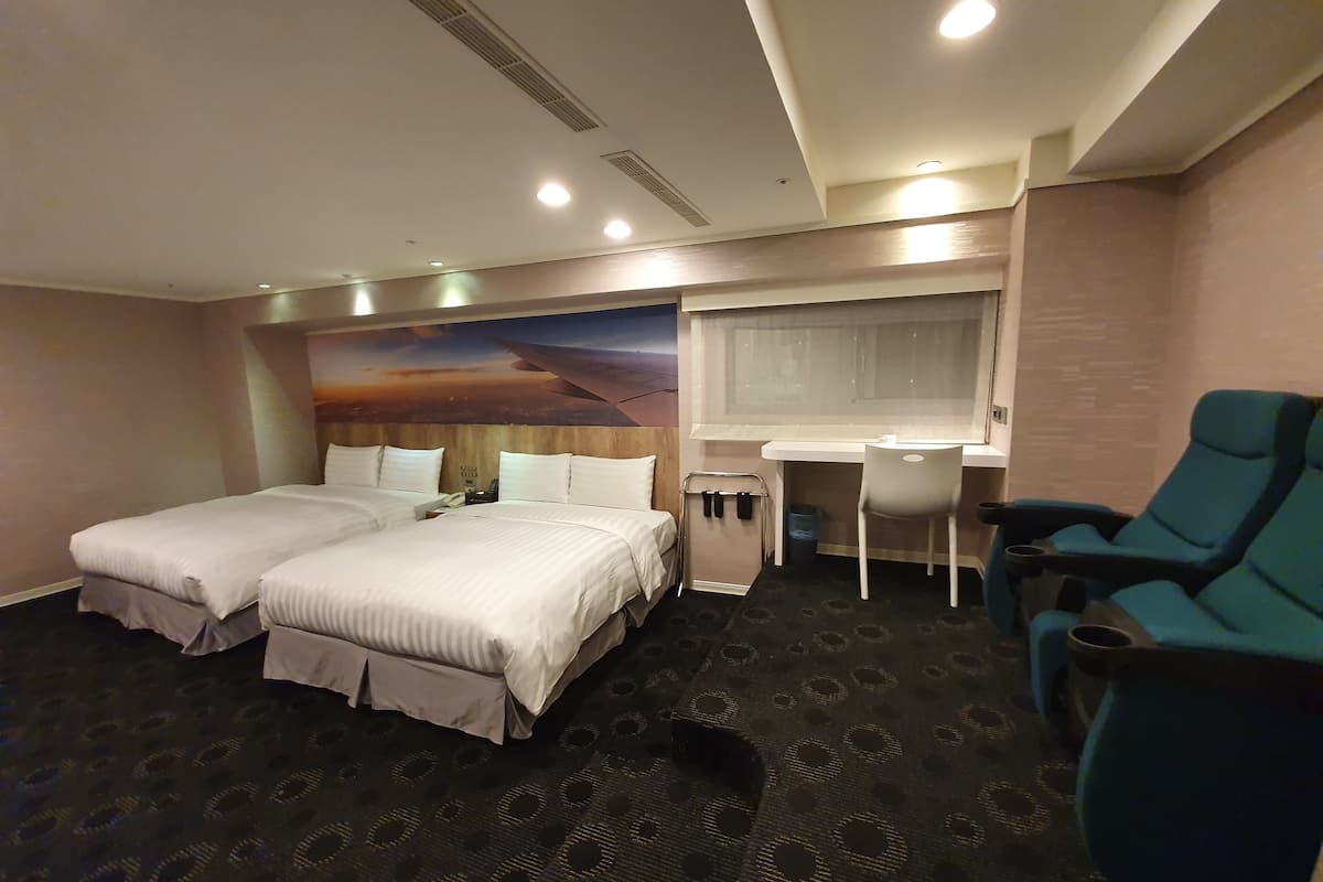 Een hotelkamer met twee bedden, een bureau, een stoel en een groot raam.