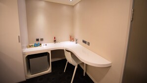 A modern bathroom with a white countertop, a built-in sink, and a compact toilet. - Ximen Airline Hotel (Taipei)
