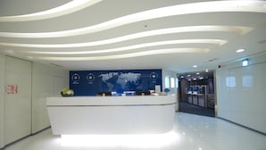 A modern reception desk with a world map and a digital display. - Ximen Airline Hotel (Taipei)
