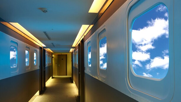 A train interior with overhead lighting, windows with sky views, and a central aisle. - Ximen Airline Hotel (Taipei)