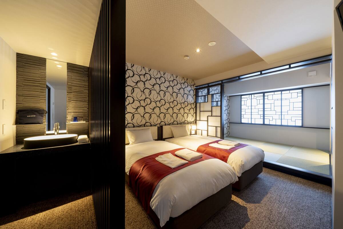 A modern hotel room with a large bed, a bedside table, a mirror, and a window with a view.