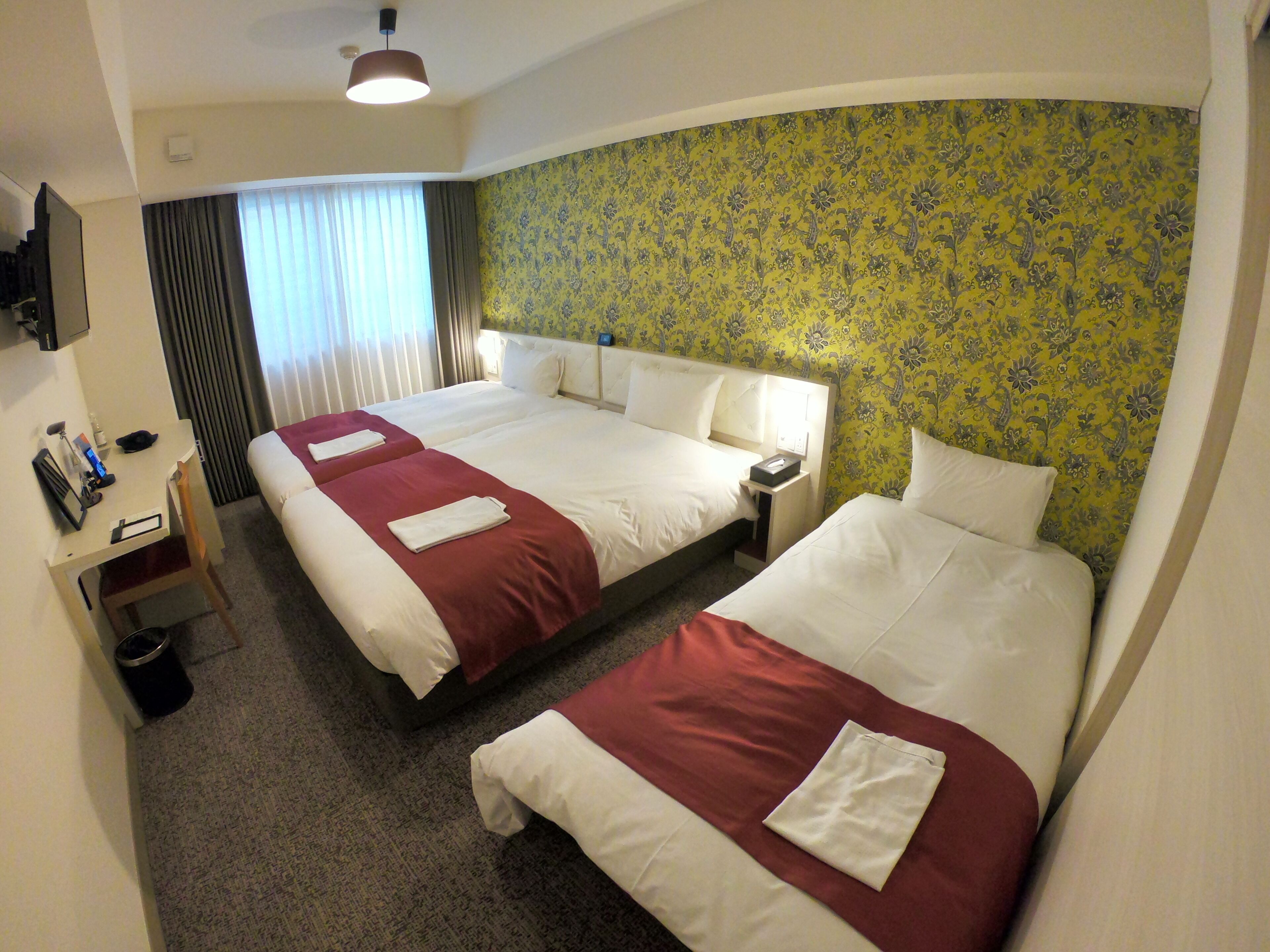 Habitación de hotel con dos camas, un escritorio y un televisor.