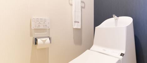 Un baño moderno con un inodoro blanco, un dispensador de toallas de papel y un perchero.