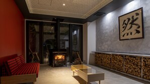 A modern living room with a sofa, a coffee table, a fireplace, and a large framed artwork on the wall. - Hotel Rosso Karuizawa (Karuizawa)
