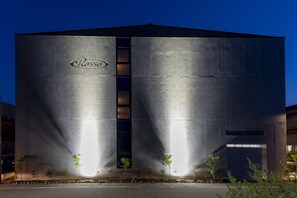A large industrial building with a prominent 'Rosso' logo, featuring a central vertical window and multiple smaller windows. - Hotel Rosso Karuizawa (Karuizawa)