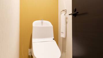 Un baño pequeño y moderno con un inodoro blanco, una toalla colgada en un perchero y una puerta con manija.