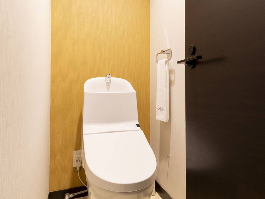 Un baño pequeño y moderno con un inodoro blanco, una toalla colgada en un perchero y una puerta con manija.