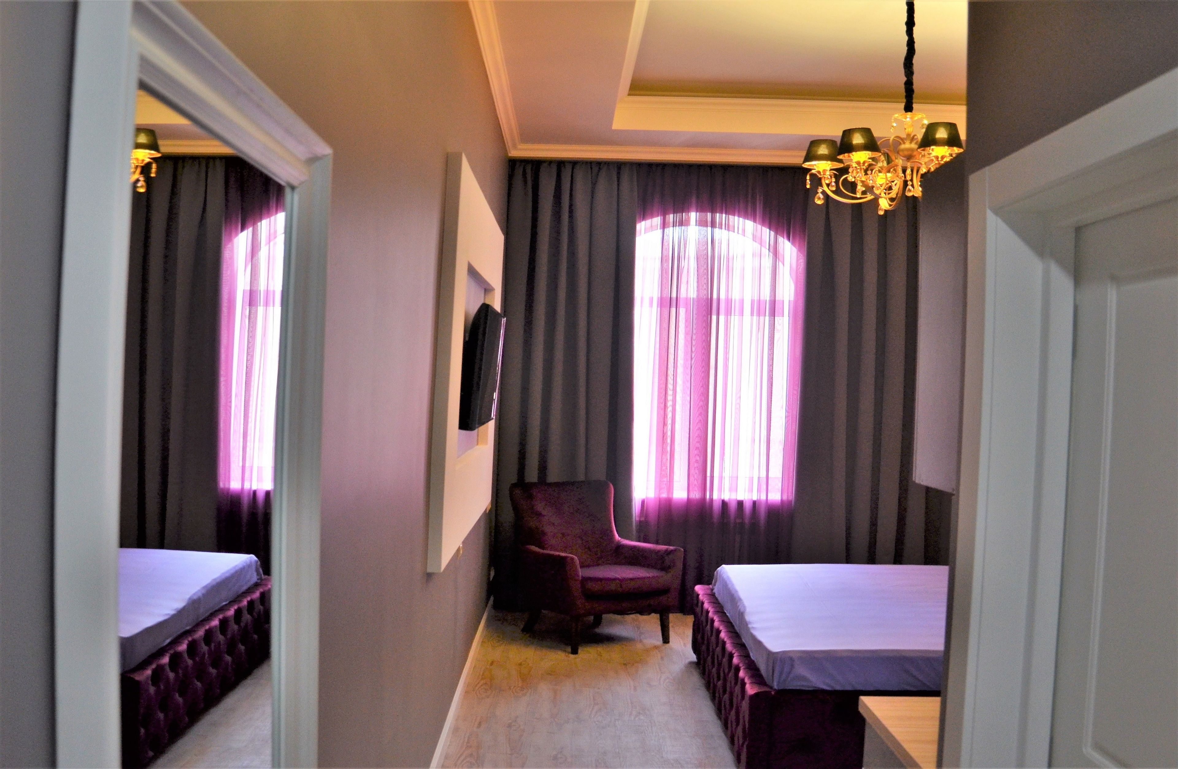 Una camera d'albergo con un letto, una sedia e un lampadario.