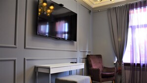 A modern living room with a flat-screen TV mounted on the wall, a white console table, a plush armchair, and a grey ottoman. - Kyiv City Center (Kyiv)