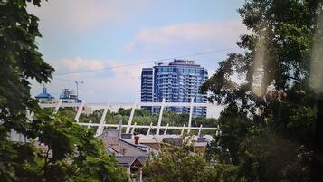 A high-rise building with a modern architectural design, surrounded by greenery and a bridge in the foreground.