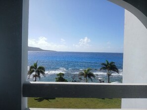 A view from a balcony overlooking the ocean with palm trees and a clear sky. - Hotel Valentino (Rota)