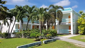 Un hôtel moderne à l’architecture contemporaine, composé de deux étages, et entouré d’une végétation luxuriante et de palmiers.