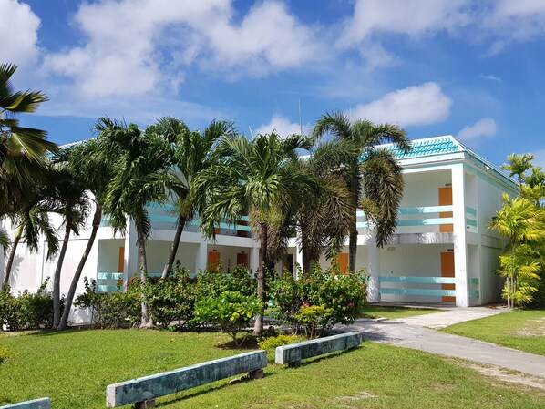 A modern hotel with a two-story structure, surrounded by lush greenery and palm trees. - Hotel Valentino (Rota)