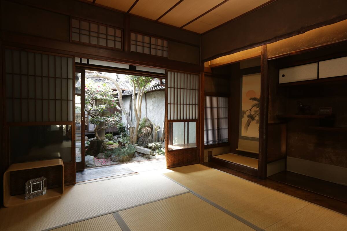 Een traditionele Japanse kamer met tatami vloerbedekking, schuifdeuren en uitzicht op een tuin.
