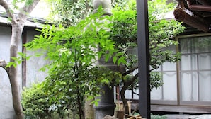 Ein traditioneller japanischer Garten mit einer Steintonne, einem Bambuskorb und verschiedenen Pflanzen und Steinen.