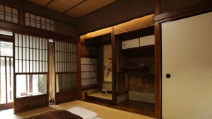Ein traditioneller japanischer Raum mit Tatami-Böden, Schiebetüren und einem niedrigen hölzernen Bett.
