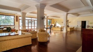 Un amplio salón con techos altos, ventanas grandes y piso de madera.