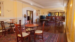 Un comedor amplio con varias mesas y sillas de madera, un televisor y un arco decorativo.