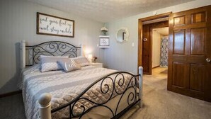 Une chambre à coucher comprenant un lit, une table de chevet, un miroir fixé au mur et une porte.